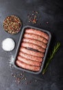 Raw beef and pork sausage in plastic tray with salt and pepper on black background Royalty Free Stock Photo