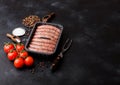 Raw beef and pork sausage in plastic tray with vintage fork on black background.Salt and pepper with tomatoes and rosemary.Space Royalty Free Stock Photo