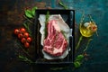 Raw beef ribeye steak on the bone with thyme, rosemary and spices.  Flat lay top view on black stone cutting table Royalty Free Stock Photo