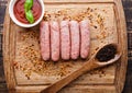 Raw beef sausages with pepper spoon and sause on board Royalty Free Stock Photo