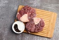 Raw beef shank with salt and pepper on a rectangular cutting wooden board on a dark background Royalty Free Stock Photo