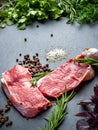 Raw beef and spices. Slices of fresh raw meat, rosemary and fresh herbs on a black slate stone plate. Preparing and marinating Royalty Free Stock Photo