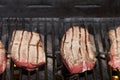 Raw beef steak cooking over flaming grill Royalty Free Stock Photo