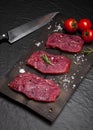 Raw beef steak on a cutting board with rosemary and cherry tomatoes. Royalty Free Stock Photo