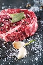 Raw beef steak fillet with ingredients like sea salt, pepper, bay leaves and onion on black board, image for restaurant, Royalty Free Stock Photo