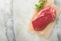 Raw beef steak. Fresh beef rib eye steak with fork rosemary, salt and pepper on piece of parchment paper on dark grey stone Royalty Free Stock Photo