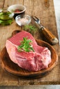 Raw beef steak. Fresh beef rib eye steak with fork rosemary, salt and pepper on piece of parchment paper on old wooden background Royalty Free Stock Photo