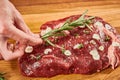 Raw beef steak seasoning with garlic slices and branch of fresh rosemary Royalty Free Stock Photo