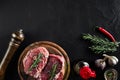 Raw beef steak with spices and ingredients for cooking on cutting board and slate background. Top view. Royalty Free Stock Photo