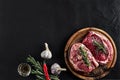 Raw beef steak with spices and ingredients for cooking on cutting board and slate background. Top view. Royalty Free Stock Photo