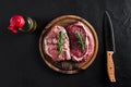 Raw beef steak with spices and ingredients for cooking on cutting board and slate background. Top view. Royalty Free Stock Photo