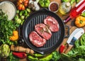 Raw beef steaks in iron pan with vegetables and wine Royalty Free Stock Photo