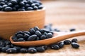 Raw black beans in wooden bowl and spoon on table