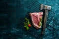 Raw bone steak with an ax. Top view. Royalty Free Stock Photo