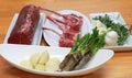 Raw boneless beef, bone rib-eye steak on a plate with onion, garlic and garnish ready to cook. Preparing ingredients on a wooden Royalty Free Stock Photo