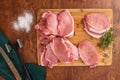 Pork loin chops on a wooden cutting board with some ingredients on wooden background Royalty Free Stock Photo