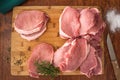 Raw boneless pork loin chops on wooden cutting board with some herbs, salt, and rosemary Royalty Free Stock Photo