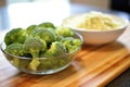 raw broccoli beside bowl of cooked broccoli rice Royalty Free Stock Photo