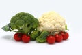 Raw broccoli, cauliflower and some red tomatoes on a light background.