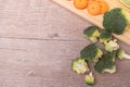Raw Broccoli on Wooden Chopping Board with Carrots in the Backdrop Royalty Free Stock Photo