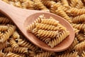 Raw brown pasta on a wooden spoon