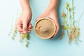 Raw brown quinoa seed in a wooden bowl with spoon holding by hand