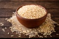 Raw brown rice in ceramic bowl on dark rustic wooden background Royalty Free Stock Photo