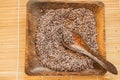 Raw brown rice on a square wooden plate and wooden spoon on a bamboo napkin for healthy eating, vegetarianism, top view, flat lay