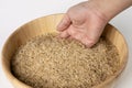 Woman`s hand is pouring raw brown rice packed in a plastic bag onto a wooden bowl Royalty Free Stock Photo
