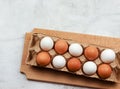 Raw brown and white chicken eggs in a cassette on a wooden cutting board on a light gray background. Royalty Free Stock Photo