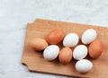 Raw brown and white chicken eggs on a wooden cutting board on a light gray background Royalty Free Stock Photo