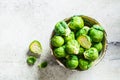 Raw brussels sprouts in bowl, gray concrete background, top view. Healthy vegan food concept