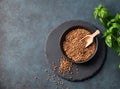 Raw buckwheat grains in a wooden bowl on a board on a dark background with fresh herb