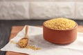 Raw bulgur in a clay bowl on a wooden board