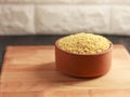 Raw bulgur in a clay bowl on a wooden board