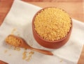 Raw bulgur in a clay bowl on a wooden board