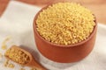 Raw bulgur in a clay bowl on a wooden board