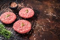 Raw burger cutlet from beef meat with spices and rosemary ready for cooking. Dark background. Top view. Copy space Royalty Free Stock Photo