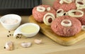 raw burgers, beef on a cooting board, frying pan on woogen background Royalty Free Stock Photo