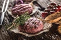 Raw burgers on wooden table with onion tomatoes herbs and spices Royalty Free Stock Photo