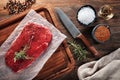 Raw calf beefsteak on white cooking paper and wooden cutting table