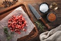 Raw calf meat chopped into small pieces on white cooking paper and wooden cutting table