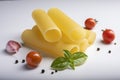 Raw cannelloni pasta on white background with cherry tomatoes, garlic and basil. Royalty Free Stock Photo