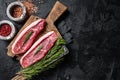 Raw cap rump beef meat steak or top sirloin on butcher board. Black background. Top view. Copy space Royalty Free Stock Photo