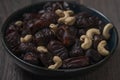 Raw cashew nuts and figs served in black bowl .