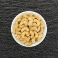 Raw cashews in a small bowl on a slate table