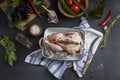 Raw chicken in a baking dish on a kitchen towel on a dark background.