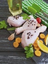 Raw chicken bird legs, lemon, garlic, parsley, dinner carrots, prepare oil on a black wooden background Royalty Free Stock Photo