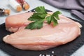 Raw chicken breast fillet, raw chicken meat on a black stand, gray background