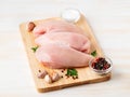 Raw chicken breast fillet with spices on wooden board on white wooden table, side view Royalty Free Stock Photo